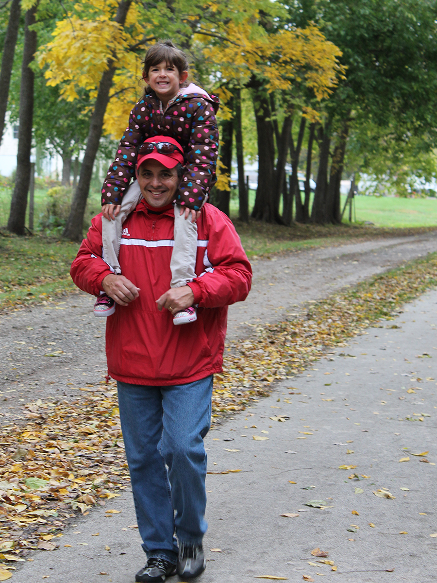 man walking on path with child on shoulders