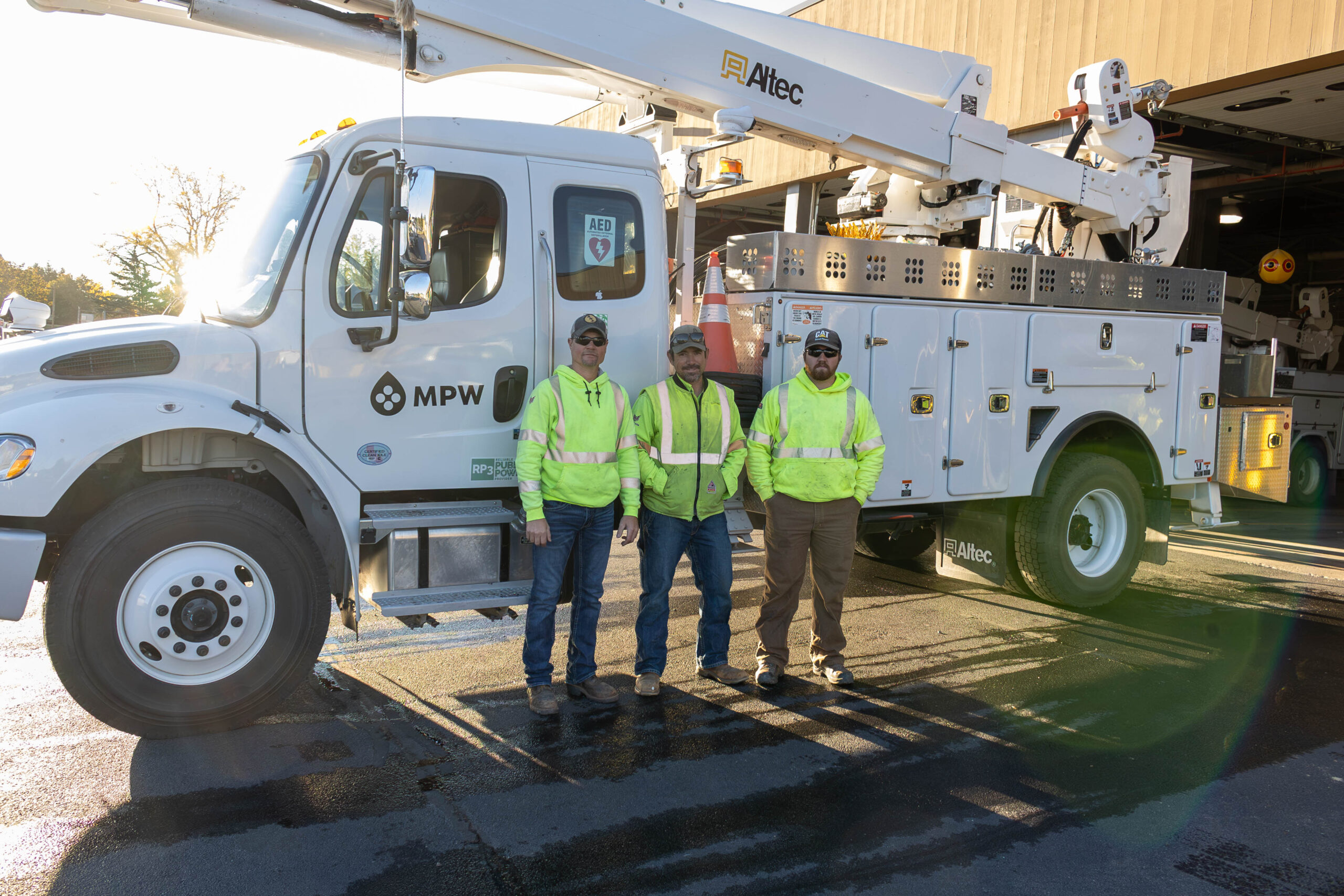 3 linemen standing by bucket truck