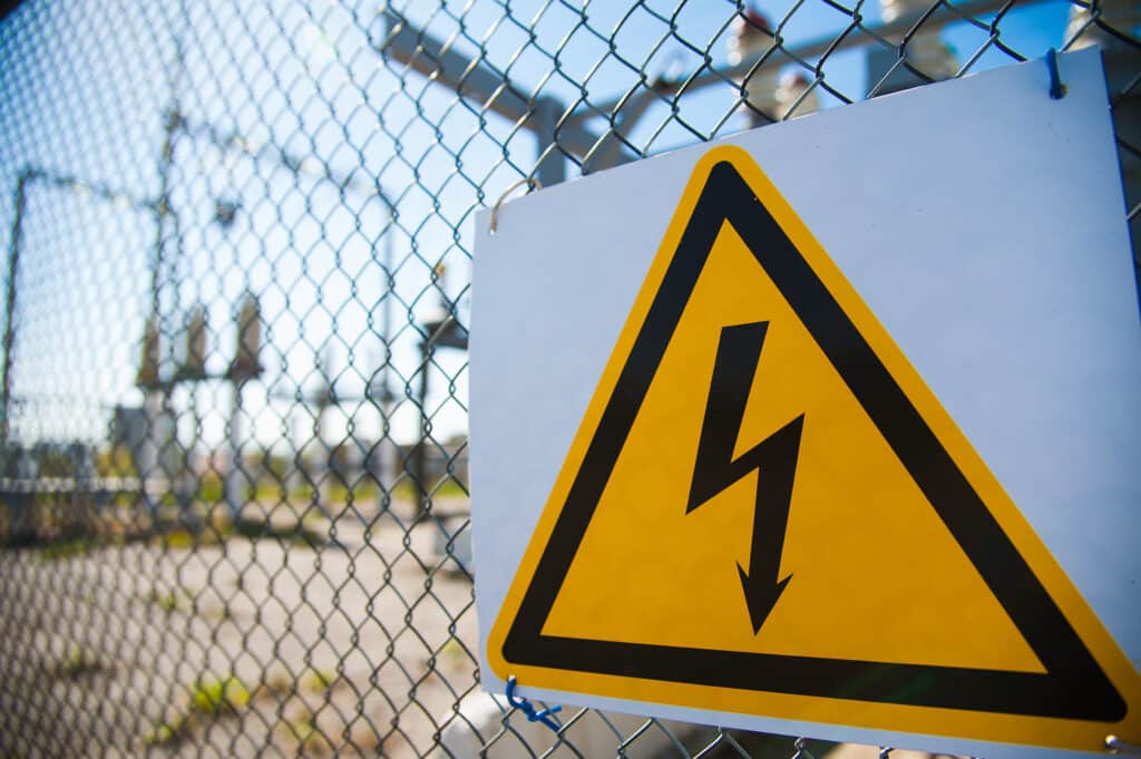 Picture of an electric hazard sign on a metal fence 