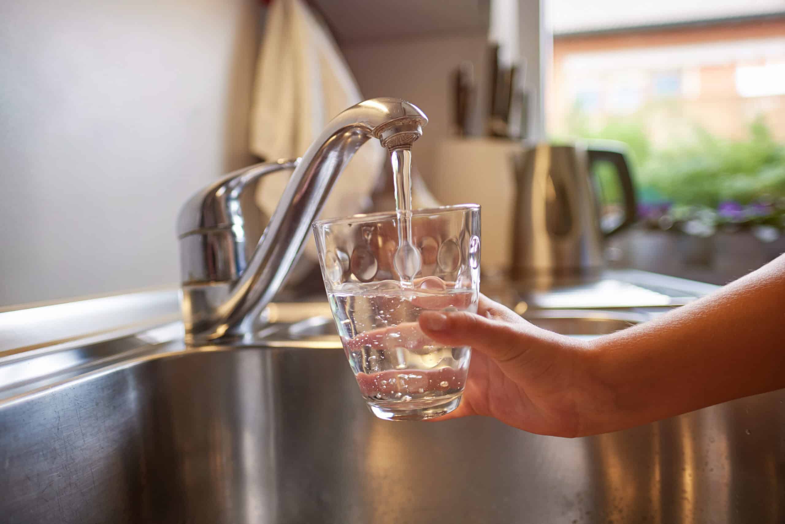 Close up of children hands, pouring glass of fresh water from tap