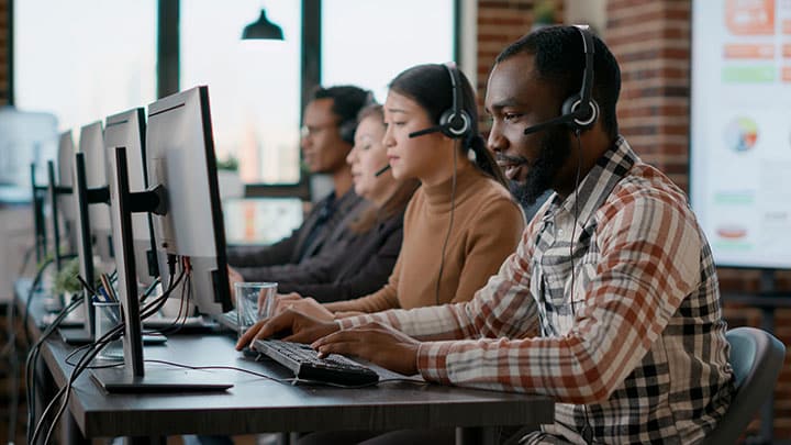 Group of people working on computers with phone headsets on