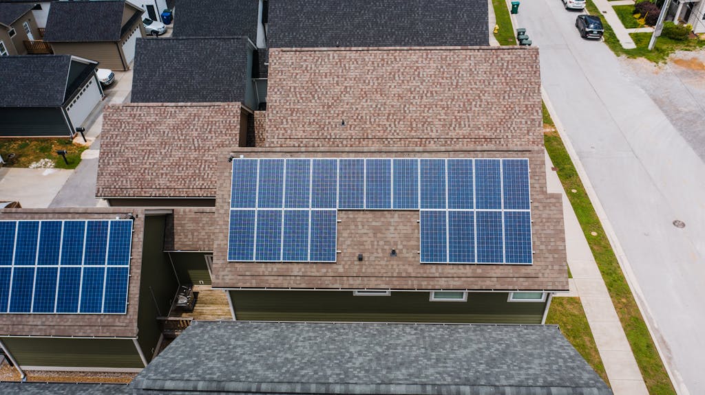 Drone shot of solar panels on residential roofs promoting eco-friendly energy solutions.