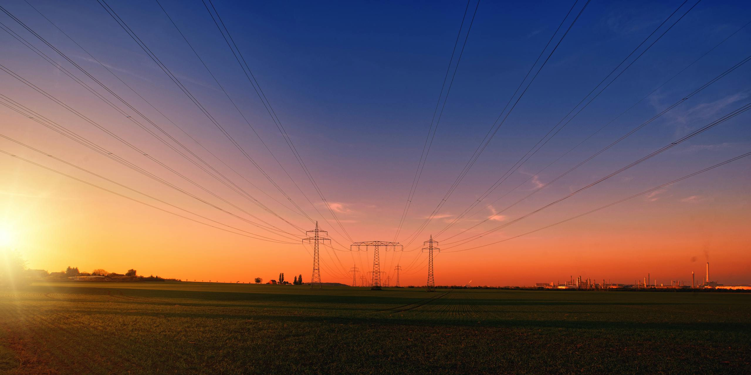 Power lines stretch across a rural landscape at dusk, capturing the serene beauty of the energy infrastructure.