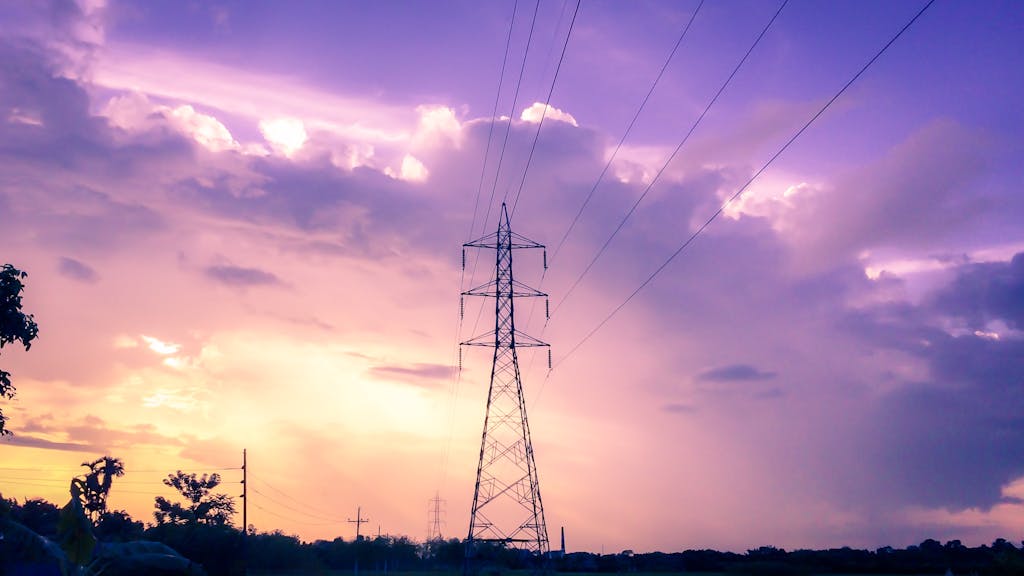 Silhouette of power lines at sunset against vibrant purple and orange sky.